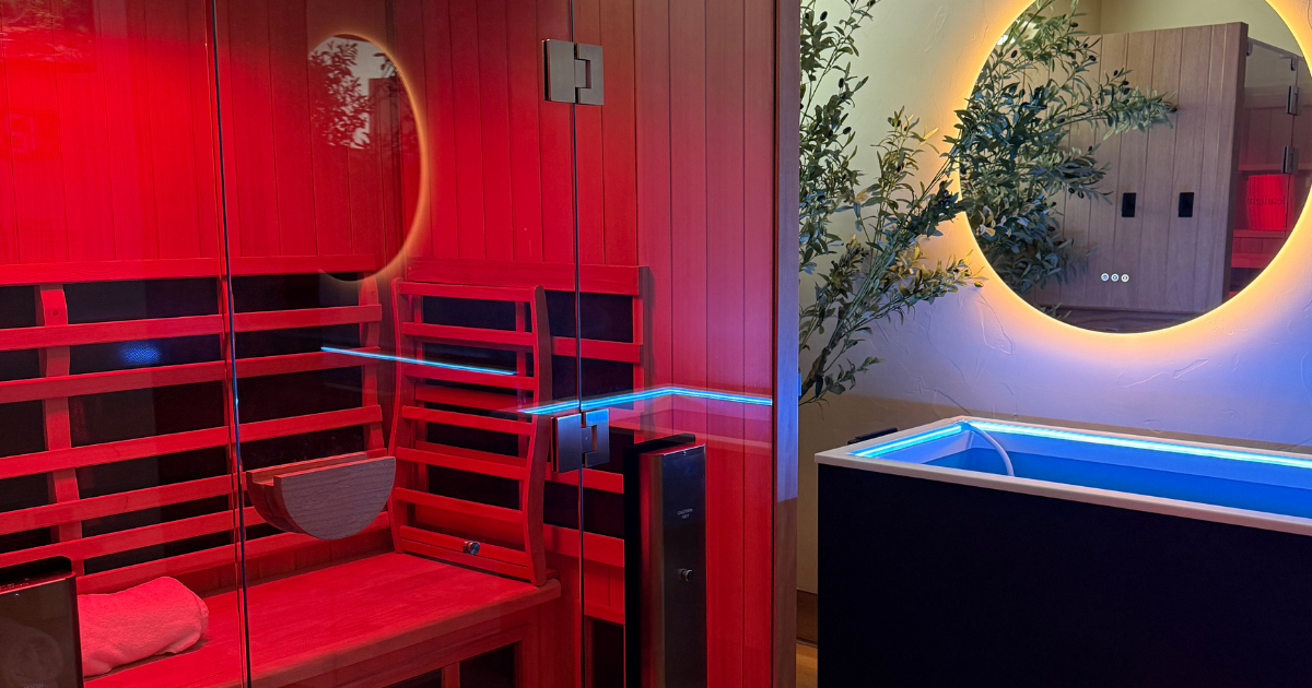 Contrast Therapy Suite at Be Well features an infrared sauna glowing with red light and a cold plunge glowing with blue light.