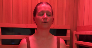 Women sitting in infrared sauna breathes with her eyes closed at Be Well in Longmont, CO.