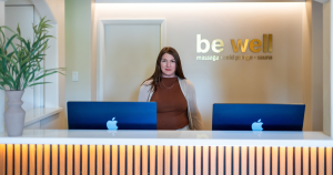 Owner of Be Well Bodyworks, Kelly, standing behind the front desk.