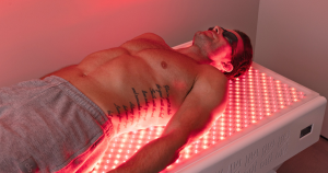 A man lays in a red light therapy bed.